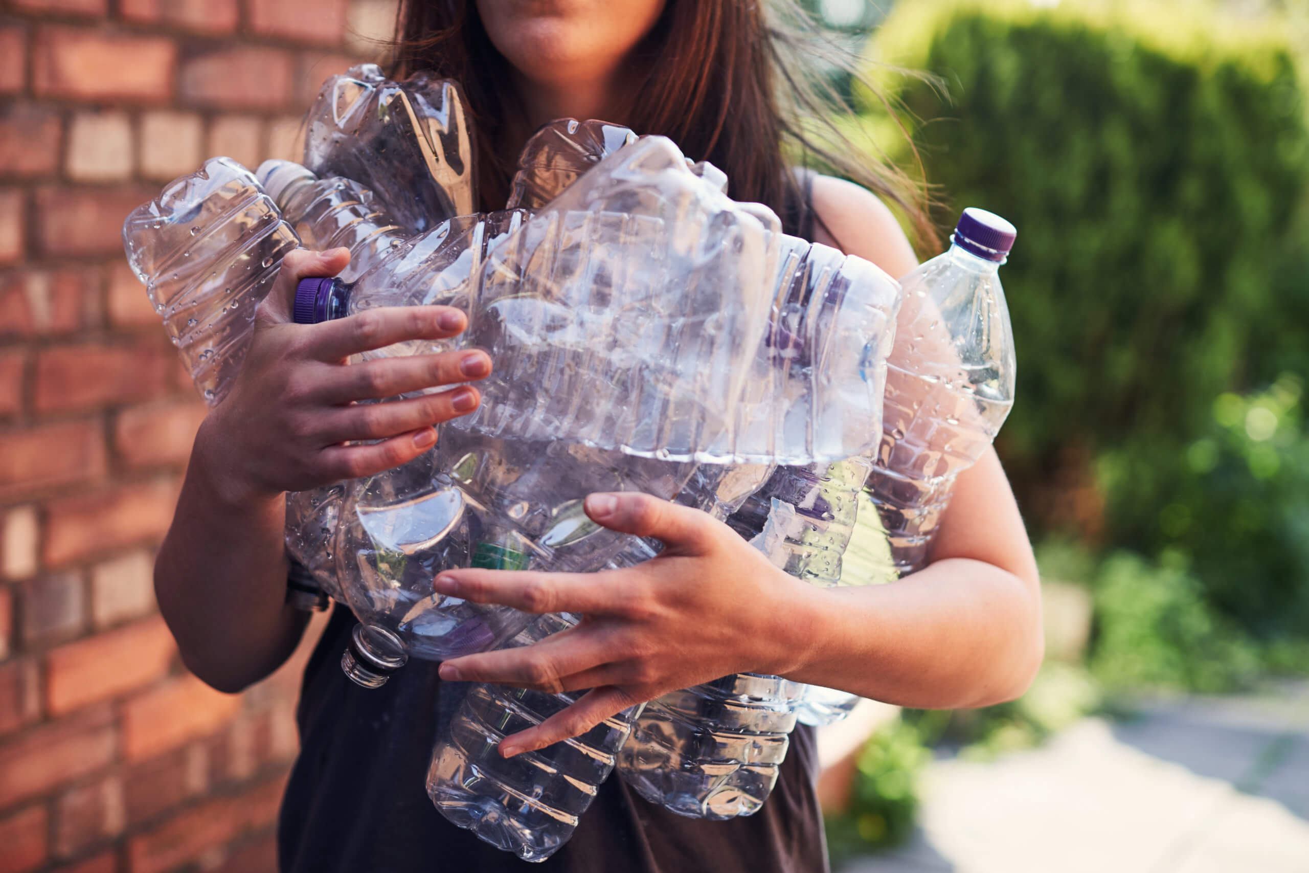 imagem de mulher a agarrar garrafas de plastico para reciclagem